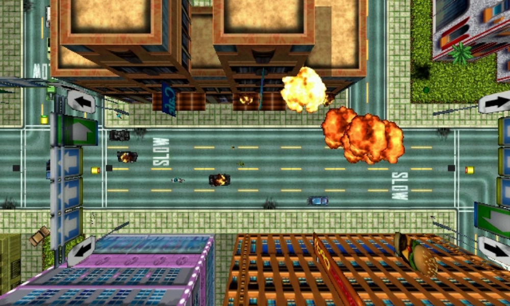 Top-down view of a city street with burning cars and explosions in the original Grand Theft Auto from 1997